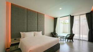 Une chambre d’hôtel moderne, dotée d’un grand lit, d’une petite table, de deux chaises et offrant une vue sur l’extérieur grâce à de grandes fenêtres.