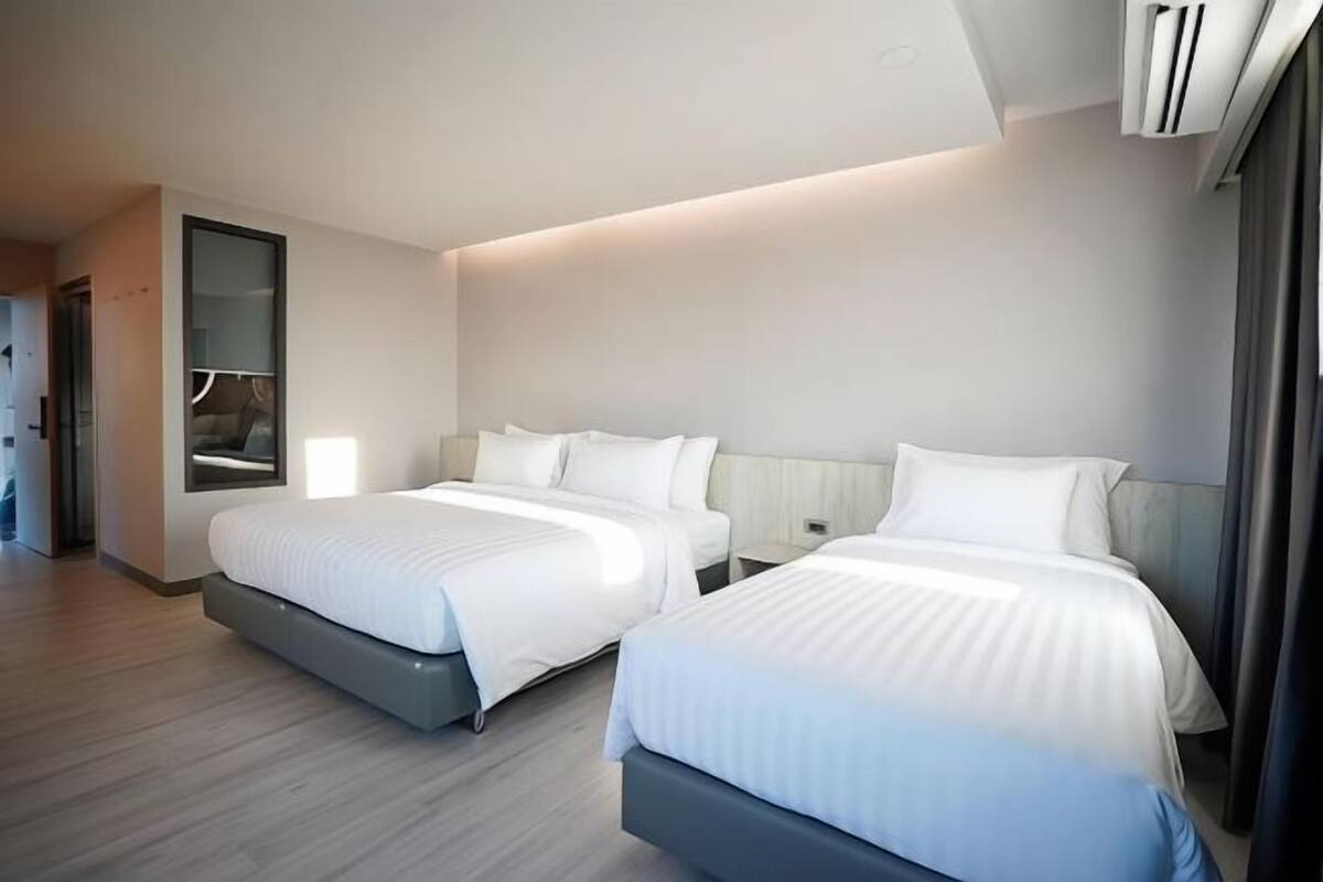 Une chambre d’hôtel avec deux lits, un grand miroir et un design moderne.