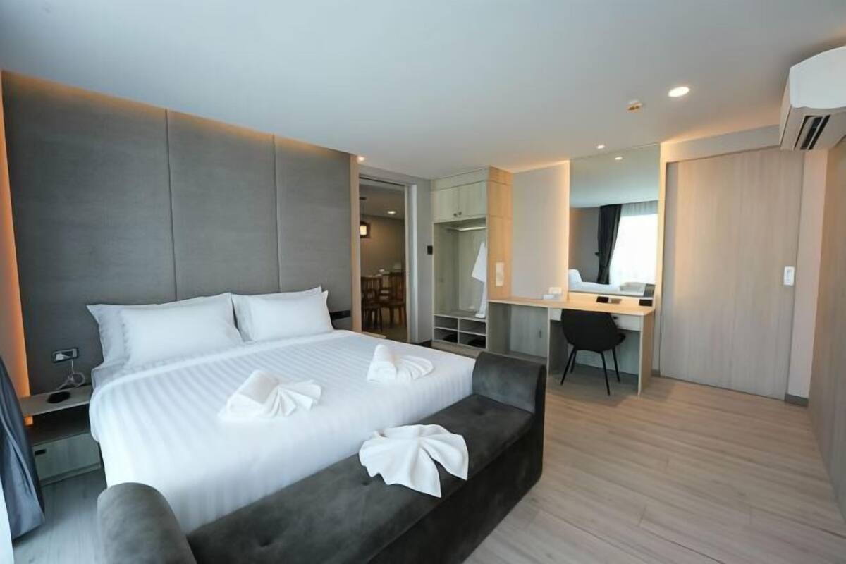Une chambre d’hôtel moderne avec un grand lit, un bureau et un dressing.