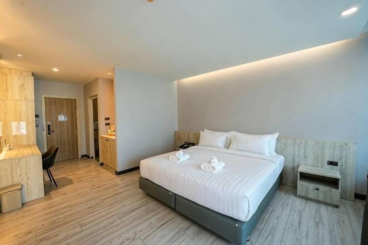 Une chambre d’hôtel moderne avec un grand lit, un bureau et une petite table de chevet.