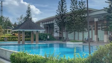 A swimming pool with a gazebo, surrounded by trees and modern buildings.