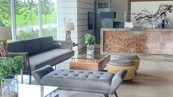 A modern hotel lobby with a sofa, a round table, and a reception desk.