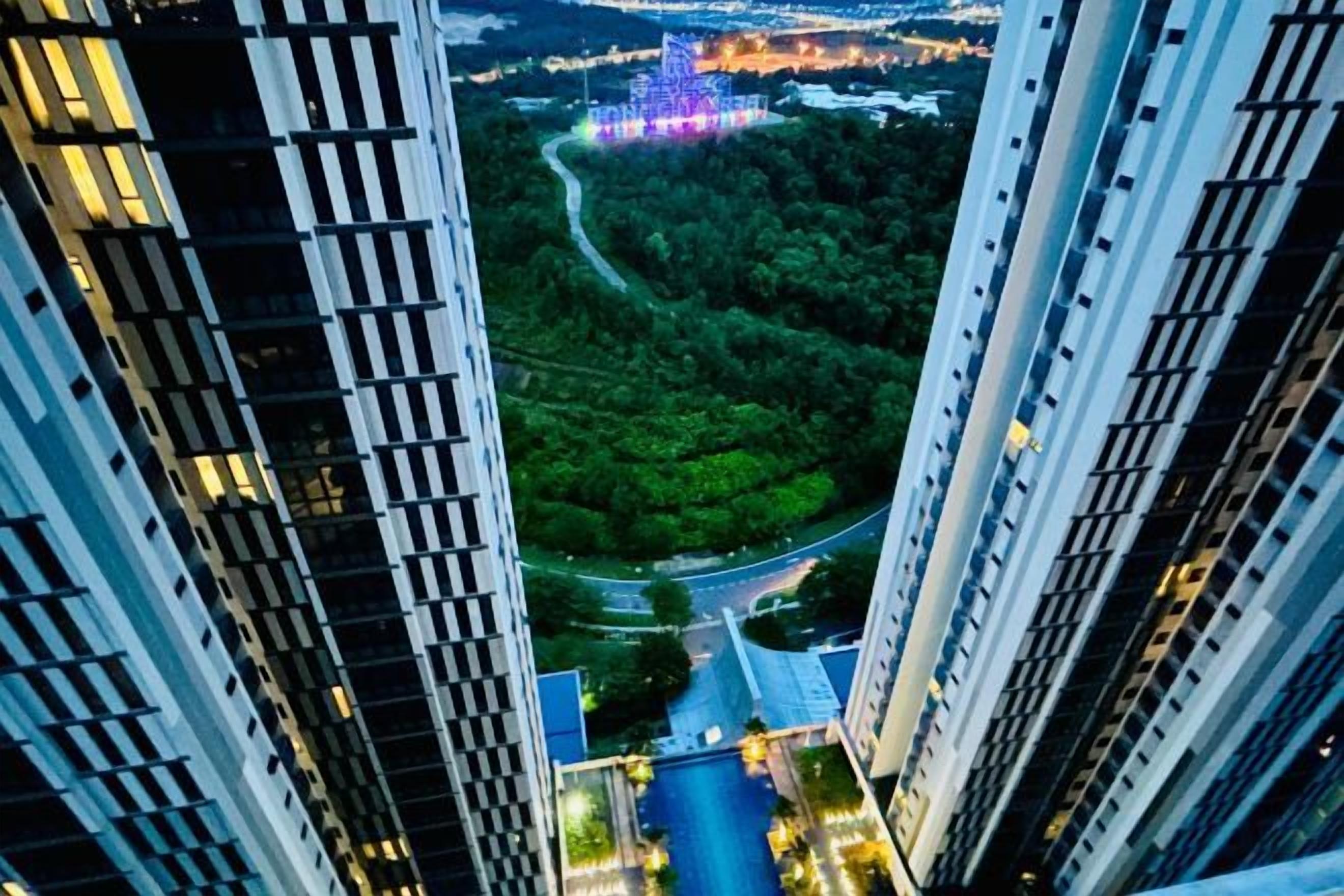 A high-rise building with a view of a river and greenery below.