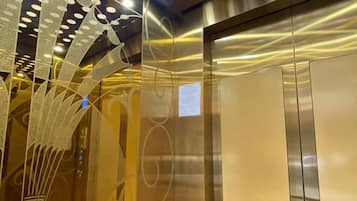 An elevator interior with metallic walls and a reflective surface.