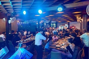 A busy restaurant with multiple dining tables and patrons.