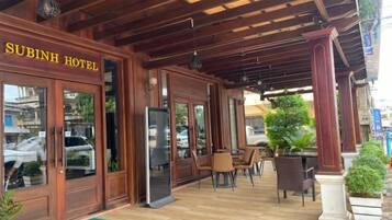 A wooden exterior of Subinh Hotel with a covered outdoor seating area.