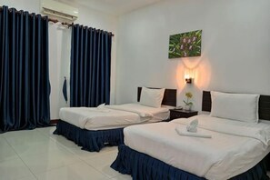 A hotel room with two beds, a nightstand, a wall-mounted lamp, and a painting.
