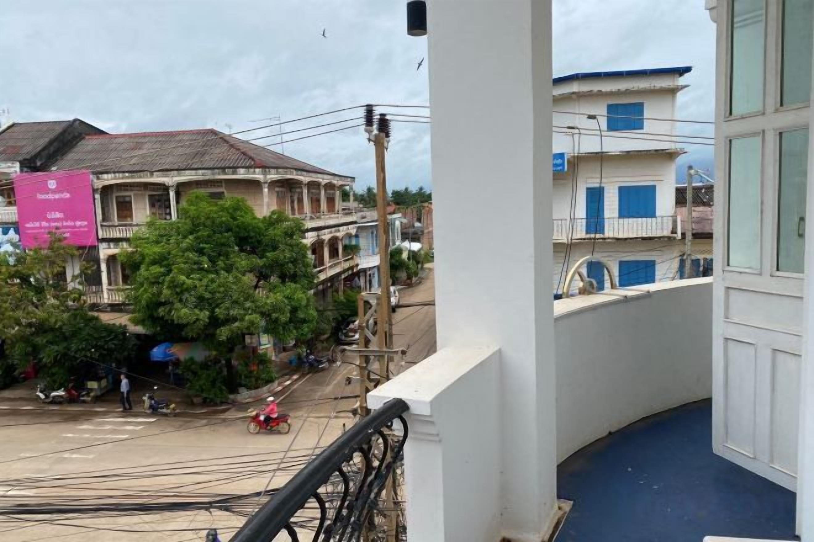 A balcony with a view of a street, buildings, and a signboard.