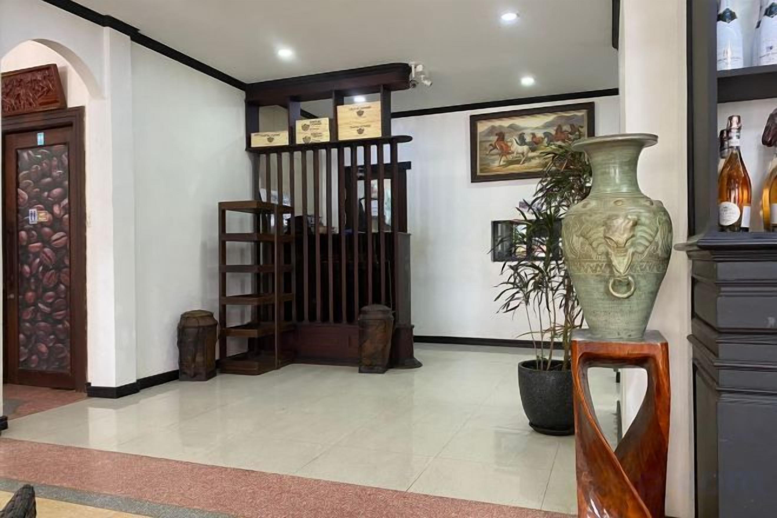 Un área de recepción con un mostrador de madera, un jarrón grande y una planta en maceta.