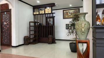 Un área de recepción con un mostrador de madera, un jarrón grande y una planta en maceta.