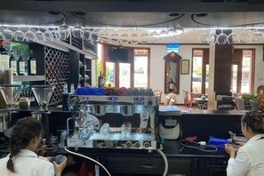 A bar area with a coffee machine, glasses, and bottles. - Subinh Hotel (Pakse)