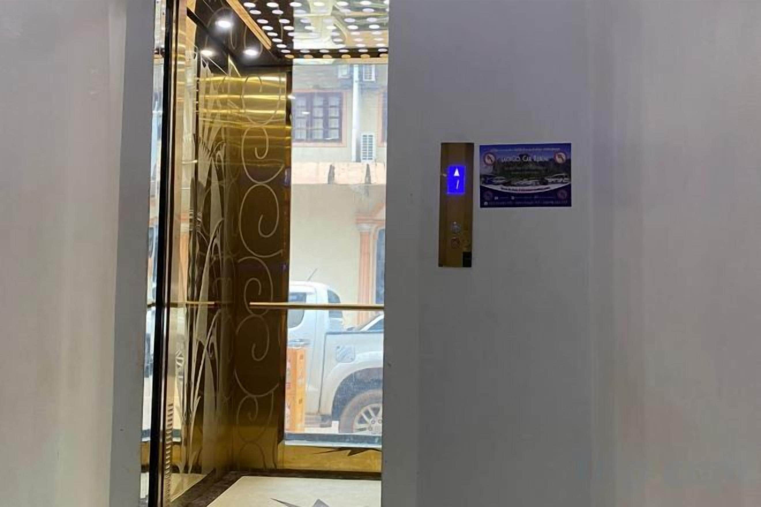 An elevator with a glass door, a digital display, and a sign with a nighttime scene.