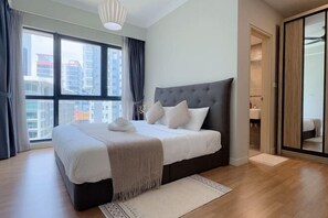 A modern bedroom with a large bed, a view of the city through large windows, and a walk-in closet. - Kuala Lumpur Sunway Velocity City Homestay (Kuala Lumpur)