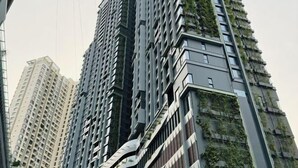 Um edifício alto com um design arquitetônico singular, apresentando varandas com vegetação.