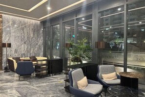 Eine moderne Lobby mit Marmorwand, Sitzgelegenheiten und großen Fenstern.