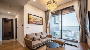 Uma sala de estar moderna com um sofá, um banquinho e uma grande janela com vista para a cidade.