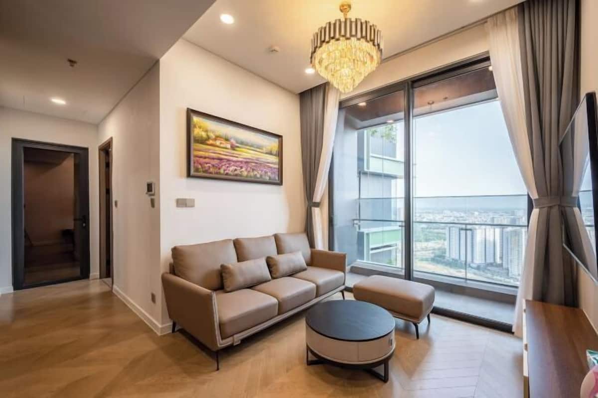 Un soggiorno moderno con divano, poggiapiedi e un'ampia finestra con vista sulla città.