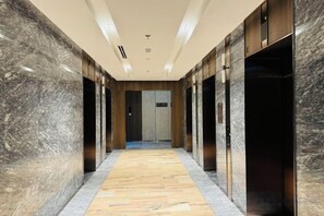 A hallway with marble walls, a patterned floor, and elevator doors. - LUMIERE RIVERSIDE CONDOTEL IN CENTER HO CHI MINH (Ho Chi Minh City)