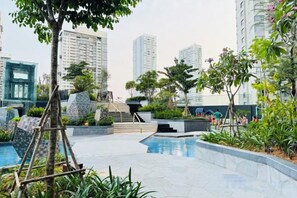 A rooftop pool area with a clear view of surrounding high-rise buildings, a small staircase, and some greenery. - LUMIERE RIVERSIDE CONDOTEL IN CENTER HO CHI MINH (Ho Chi Minh City)