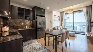 Cozinha moderna com armários escuros, bancada de mármore e área de jantar com mesa e cadeiras.