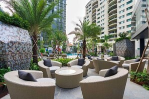 An outdoor seating area with wicker furniture and a tiled wall. - LUMIERE RIVERSIDE CONDOTEL IN CENTER HO CHI MINH (Ho Chi Minh City)