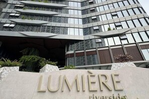 A modern building with a sign that reads 'LUMIERE riverside.' - LUMIERE RIVERSIDE CONDOTEL IN CENTER HO CHI MINH (Ho Chi Minh City)