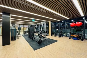 A gym with various exercise equipment, including a squat rack and weight machines. - LUMIERE RIVERSIDE CONDOTEL IN CENTER HO CHI MINH (Ho Chi Minh City)