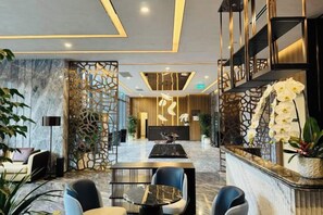 A hotel lobby with a reception desk, seating area, and decorative plants. - LUMIERE RIVERSIDE CONDOTEL IN CENTER HO CHI MINH (Ho Chi Minh City)