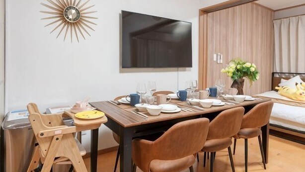 Une chambre d’hôtel moderne équipée d’une table à manger pour quatre personnes, d’un téléviseur fixé au mur et d’un lit à baldaquin.