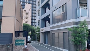 Un edifici modern d'apartaments amb diversos balcons, una entrada tancada amb reixa i una placa que indica que és un complex residencial.