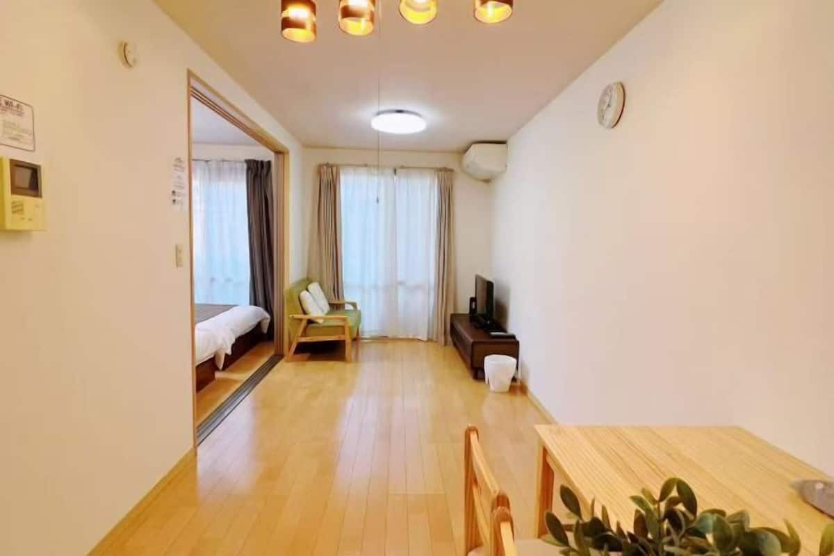 Une pièce comprenant un lit, un bureau, une chaise, un téléviseur et une plante.