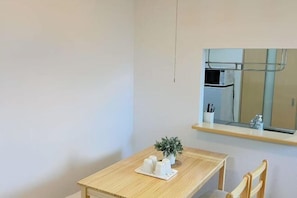 A small, clean room with a wooden table, a potted plant, and a mirror above the table. - Urban Heights Watanabedori A (Fukuoka)
