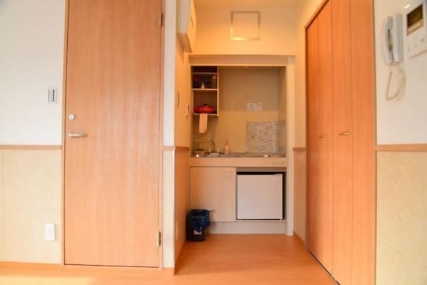 A compact kitchenette with a refrigerator, a sink, and a small countertop. - Uenohouse Family Room (Tokyo)