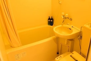 A bathroom with a bathtub, a sink, and two bottles of soap. - Uenohouse Family Room (Tokyo)