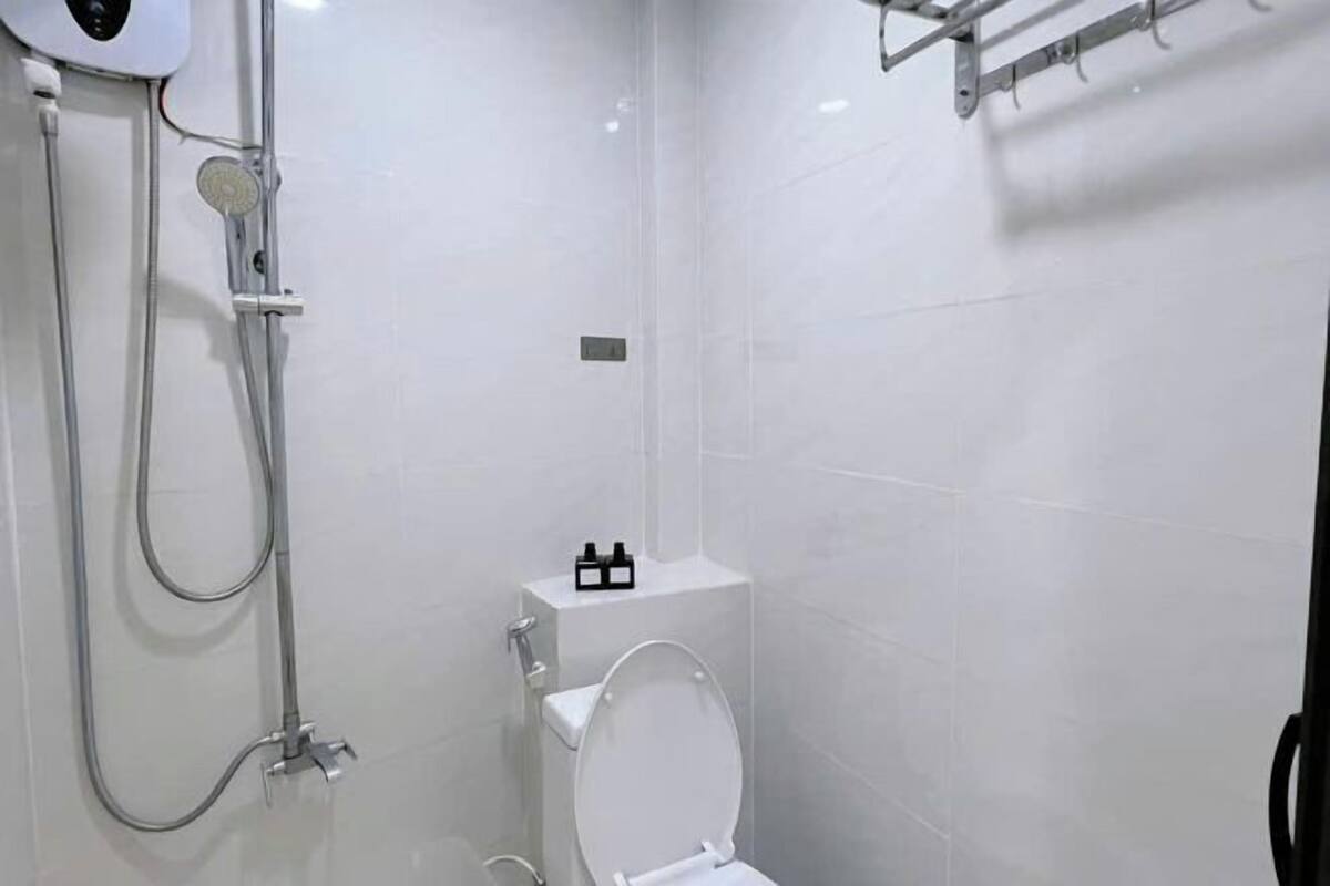 A modern bathroom with a toilet, a shower, and a towel rack.
