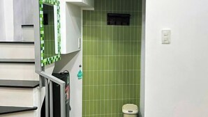 A bathroom with green tiled walls, a white sink, and a mirror. - Small Private house in Bui Vien Walking Street (Ho Chi Minh City)