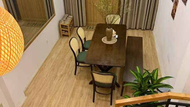 Ein Essbereich mit einem Holztisch, vier Stühlen, einer Vase mit Ästen und einer Topfpflanze.