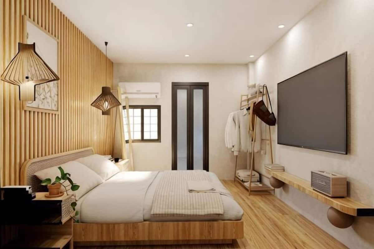 A modern bedroom with a bed, bedside table, lamp, and a TV mounted on the wall.