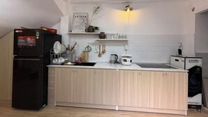 Eine moderne Küche mit einem schwarzen Kühlschrank, Holzschränken, einer weißen Arbeitsplatte und einer integrierten Spüle.