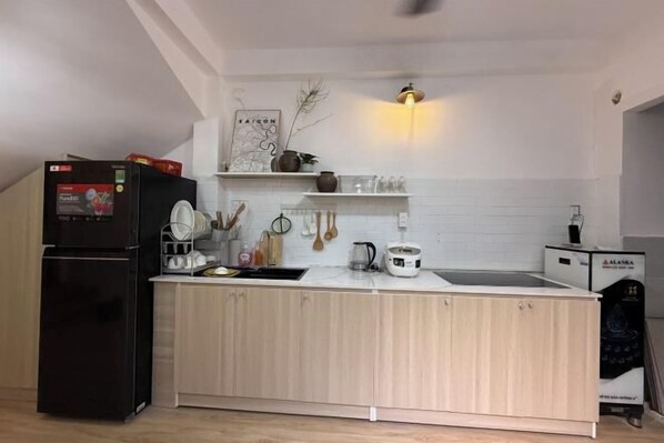 A modern kitchen with a black refrigerator, wooden cabinets, a white countertop, and a built-in sink. - LYLAC Home Saigon HHH - Beautiful City Center Whole Townhouse in D1 (Ho Chi Minh City)