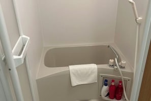 A small, white, walk-in shower with a towel hanging on the wall, a shelf with toiletries, and a showerhead. - LuckyHouse yorokobiya 901 (Osaka)