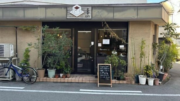 Une devanture de magasin avec une enseigne, des plantes en pot et un vélo garé à l’extérieur.