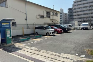 Un parking avec plusieurs voitures et un bâtiment en arrière-plan.