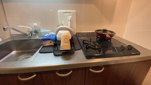 Une cuisine équipée d’un évier, d’un égouttoir, d’une cuisinière à gaz et d’une casserole.