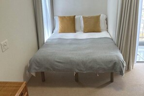 A bed with a grey bedspread and two pillows, a bedside table, and a window with curtains. - LuckyHouse yorokobiya 901 (Osaka)