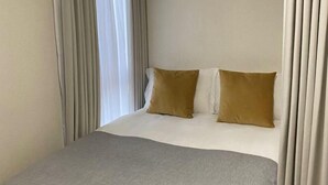 Une chambre d’hôtel avec un lit, deux oreillers et des rideaux.