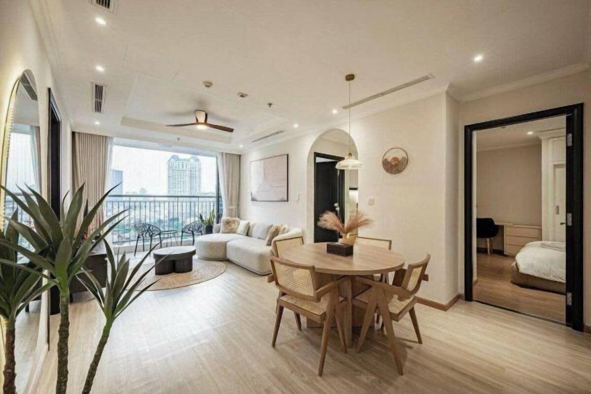 A modern hotel room with a dining area, a sofa, a bed, and a balcony with a view.