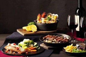 A variety of dishes including seafood, vegetables, and meat, with wine glasses and a bottle on the table. - Saigon Landmark Apartment - Vinhomes (Ho Chi Minh City)