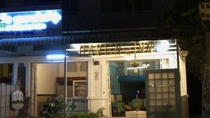 A building with a signboard, a motorcycle parked in front, and a small garden area with potted plants. - Haven Inn (Phnom Penh)