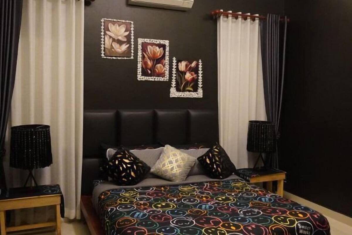 A bedroom with a bed, two nightstands, a lamp, and wall art.